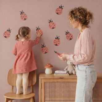 Moeder en dochter plakken rode lieveheersbeestje muurstickers op de kinderkamer muur — set van 5 stuks
